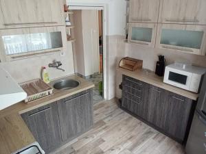 a small kitchen with a sink and a microwave at Györkös Apartman in Balatonszárszó