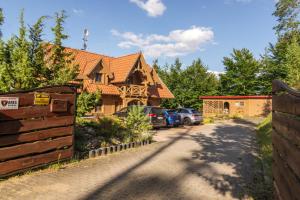 a house with cars parked in front of a driveway at Leśny Dworek Podjazy in Podjazdy