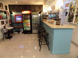 a restaurant with a bar with stools and a refrigerator at Hostal Villa Maruja in El Arenal