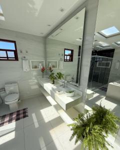 a white bathroom with two sinks and a toilet at Aruna Eco Pousada in Búzios