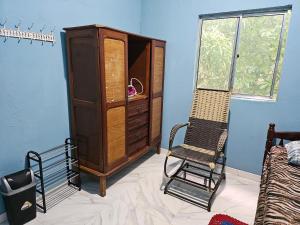 a room with a chair and a wooden cabinet at Casa florida in Marituba
