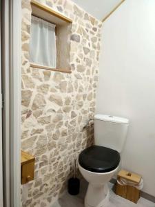 a bathroom with a black toilet with a stone wall at Gîte rural au Bois des Riots in Montillot