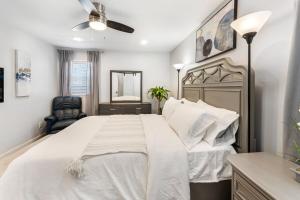 ein Schlafzimmer mit einem großen weißen Bett mit Deckenventilator in der Unterkunft Suburban 3BR Stylish Oasis in Maplewood