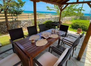 a wooden table and chairs on a patio with the ocean at Only Blue Villa in Karianí