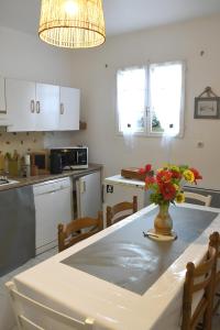 a kitchen with a table with a vase of flowers on it at Douceur et quiétude rurale in Lassay-sur-Croisne