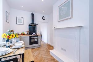 a kitchen with white walls and a table with flowers on it at Spacious & Modern House in Crewe by 53 Degrees Property, Ideal for Long Term, Sleeps 8! in Crewe