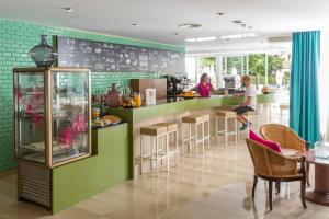 a restaurant with a bar with a woman standing at a counter at Aparthotel Cap De Mar in Cala Bona