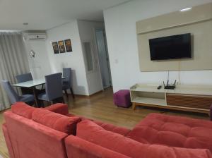 a living room with a red couch and a tv at Apartamento Cantinho do Aconchego-Nova Petrópolis in Nova Petrópolis