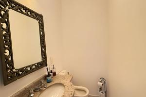 a bathroom with a sink and a mirror at Bela casa em Riviera – SP (6) in Bertioga +44 photos