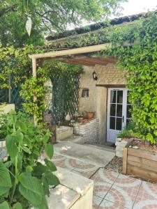 a garden with a stone building with a white door at Jasmine cottage in Prinçay