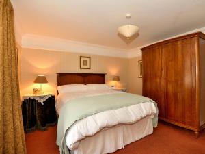 a bedroom with a large bed and a wooden cabinet at Molly's Cottage in Glenridding