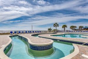 a pool at the beach with chairs and palm trees at Oceanfront TOP LOCATION MODERN RESORT Lazy River Huge Pool Oasis in Myrtle Beach