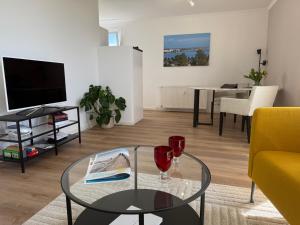 a living room with a glass table and a tv at Panoramablick Ostsee, Binnensee & Salzwiesen - Balkon - Stilvoll - Highspeed Glasfaser WLAN - Parkplatz - Ferienwohnung 'Freiheit' in Heiligenhafen