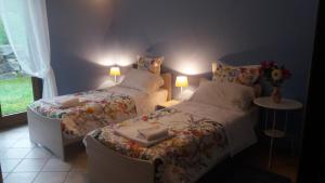 two beds in a bedroom with two lamps on at Villa Campo dei Fiori in Casciago