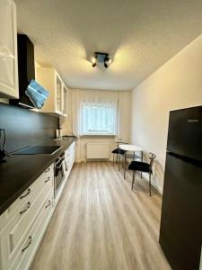 a kitchen with white cabinets and a black refrigerator at Apartment Rose in Bad Rappenau