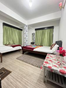 a hotel room with two beds and a table at The Oasis Holiday Home & Restaurant in Gangtok