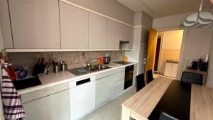a kitchen with white cabinets and a sink and a table at Walters Hostel Interlaken in Interlaken