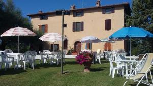 a group of tables and chairs with umbrellas in front of a building at Villa Finetti in Gubbio