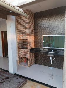 a room with a tv on a brick wall at Nova casa de praia na Caponga in Cascavel