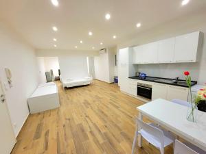 una grande cucina con mobili bianchi e pavimento in legno di Grande Bilocale in centro per Lavoratori-famiglie-ideale inverno a Mentone