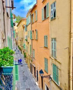 マントンにあるVieille ville Menton-ideale invernoの通りを歩く人々と建物のある路地