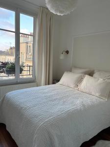 a bedroom with a white bed and a window at Cerise's home - Cosy flat 15min from Paris with hot tub in Levallois-Perret