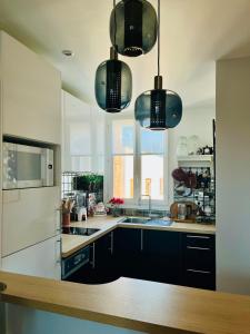 a kitchen with black cabinets and a white refrigerator at Cerise's home - Cosy flat 15min from Paris with hot tub in Levallois-Perret