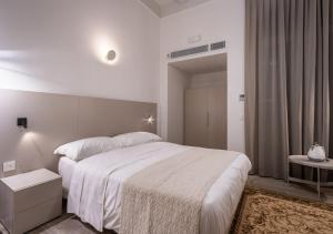 a white bedroom with a large bed and a table at Old Theatre Suites - Montecristo in Valletta