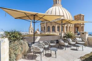 a patio with chairs and an umbrella and a building at Old Theatre Suites - Montecristo in Valletta +12 photos