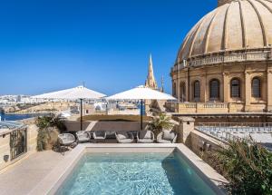 a pool with chairs and umbrellas on top of a building at Old Theatre Suites - Montecristo in Valletta