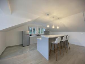 a white kitchen with a counter and stools at Apartments Marina in Bečići
