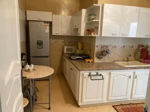 a kitchen with white cabinets and a table and a refrigerator at Logement moderne, près de la mer in Akouda