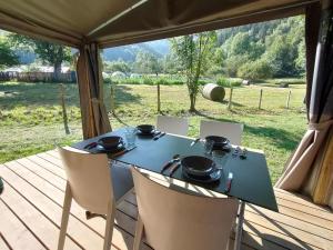 a table and chairs on a deck with a view of a field at Camping Canopée in Landry
