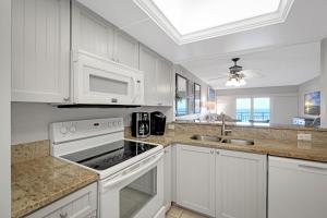 ニュー・スマーナ・ビーチにあるDirect Oceanfront Condo, No-Drive Beach, Great Beach View From Private Balconyの白いキャビネットとシンクと電子レンジを備えたキッチン