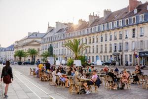a group of people sitting at tables on a city street at F3 Central, Bright and Quiet in Caen in Caen