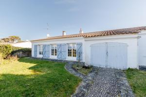 una casa blanca con una puerta y un patio en La Casa du Hameau - A 10min de la Plage, en Saint Gilles Croix de vie