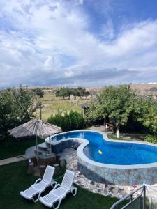 a swimming pool with two chairs and an umbrella at Guest house and yurt camp "Aktan" in Bokonbayevo