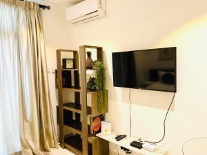 a living room with a television and a book shelf at KS Unique Studio Apartment in Accra
