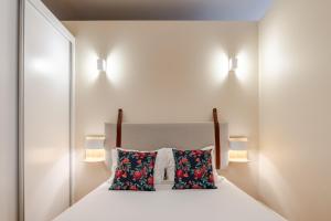 ein Schlafzimmer mit einem weißen Bett und zwei Kissen in der Unterkunft Visconde de Gandara Apartment by Porto Stories in Porto