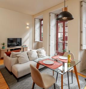 ein Wohnzimmer mit einer weißen Couch und einem Glastisch in der Unterkunft Visconde de Gandara Apartment by Porto Stories in Porto