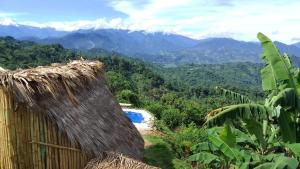 vista su una valle con una capanna e le montagne di Mirador Hostal Sierra Nevada Santa Marta a Santa Marta