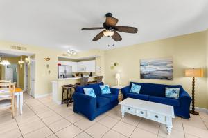 un soggiorno con divani blu e ventilatore a soffitto di Celadon #2007 a Panama City Beach