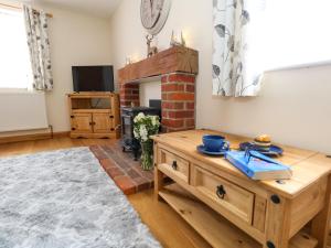 sala de estar con mesa de centro de madera y chimenea en Little Dairy House, en Swanage