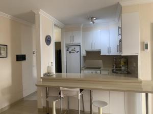 a kitchen with white cabinets and a counter with stools at Primavera Deluxe in Costa Del Silencio +2 photos