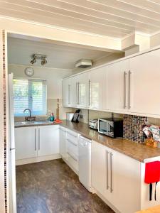 a kitchen with white cabinets and a sink at Lakefront w Hot Tub Sunset Views - Medway Lodge in South Cerney