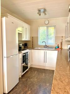 a kitchen with white cabinets and a sink at Lakefront w Hot Tub Sunset Views - Medway Lodge in South Cerney