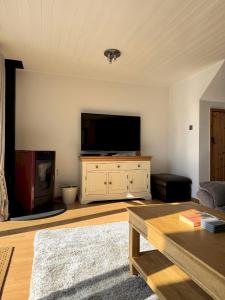 a living room with a flat screen tv on a dresser at Lakefront w Hot Tub Sunset Views - Medway Lodge in South Cerney