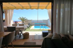 a living room with a view of a swimming pool at Villa CD30 with private heated pool in Caleta De Fuste