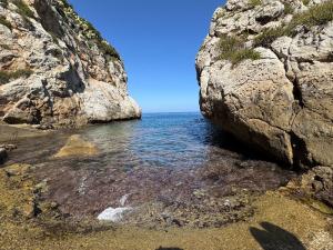 a large rock on a beach next to the ocean at AWA Kafara in Porticello +31 photos