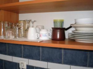 a shelf with plates and cups and dishes on it at Sunrise Flora in Agia Marina Aegina